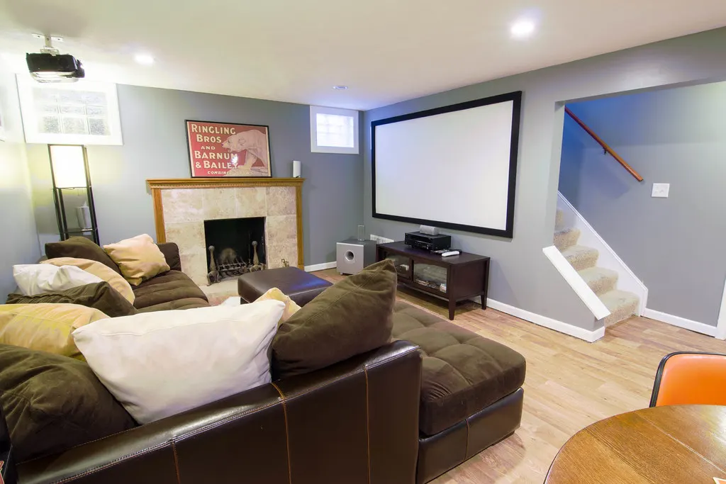 Finished basement family room with a sectional sofa and projector screen