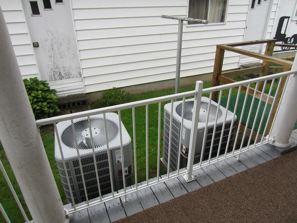 Two outdoor air conditioning units beside a house