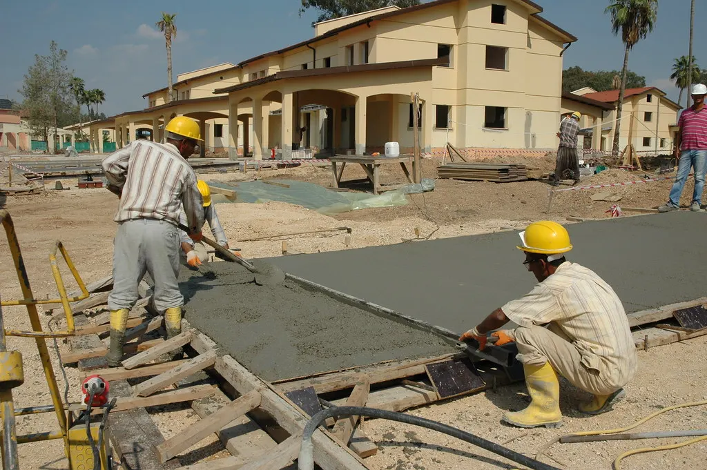 Construction workers pouring and finishing concrete on a job site