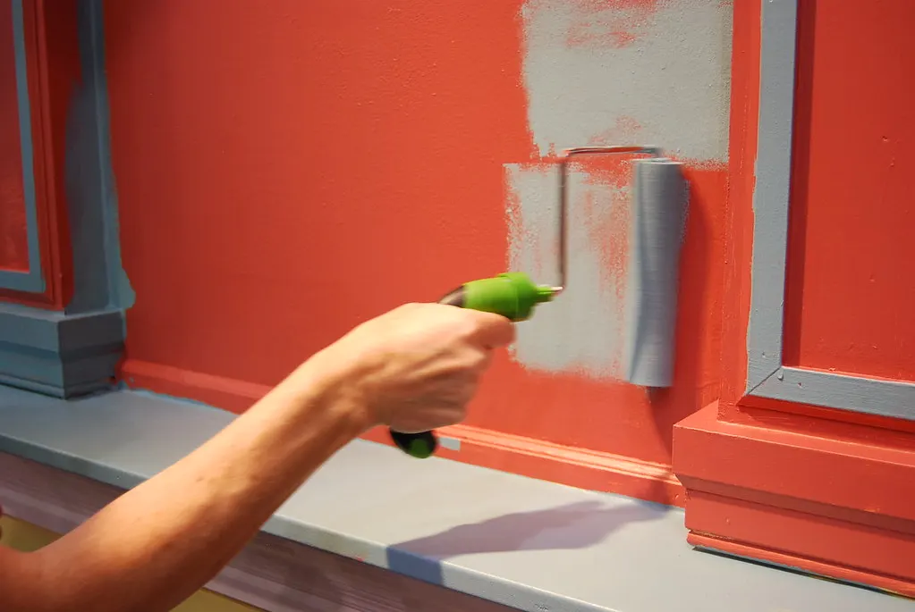 Paint roller applying a new coat of paint to a wall