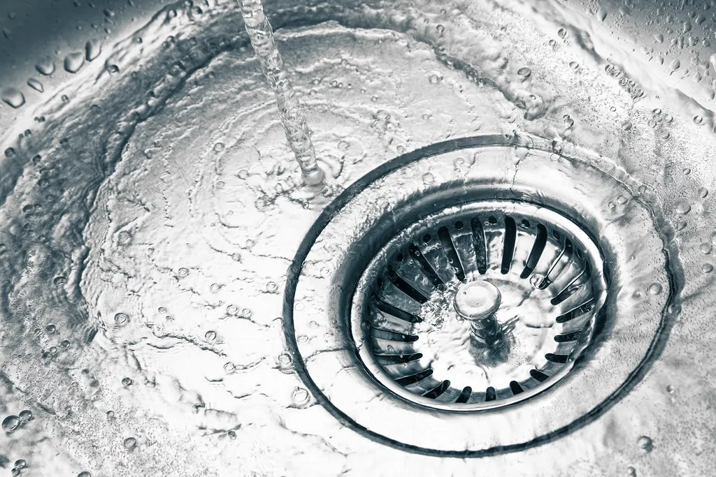 Water running into a stainless steel kitchen sink drain
