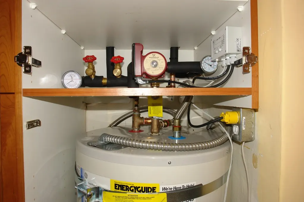 Tank water heater with pipes and valves in a utility closet